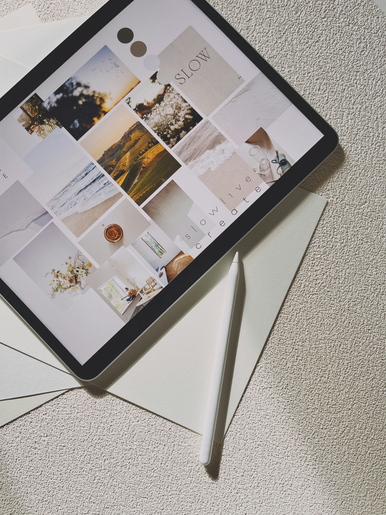 An iPad showing a mood board with an Apple Pencil on pale paper